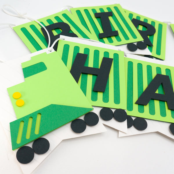 A closeup of the birthday banner fashioned to look like a green freight train. Each pennant is a cargo car with one letter on it. This photo focuses on the train engine pennant.
