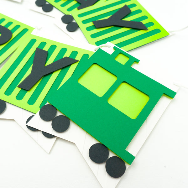 A closeup of the birthday banner fashioned to look like a green freight train. Each pennant is a cargo car with one letter on it. This photo focuses on the caboose pennant.