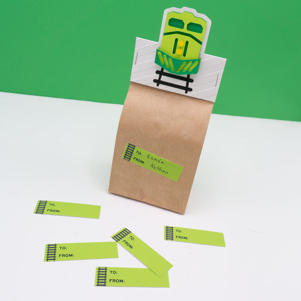 Rectangular to and from gift tag sticker labels with black railroad tracks running along the left side. Pictured here on a goodie bag.