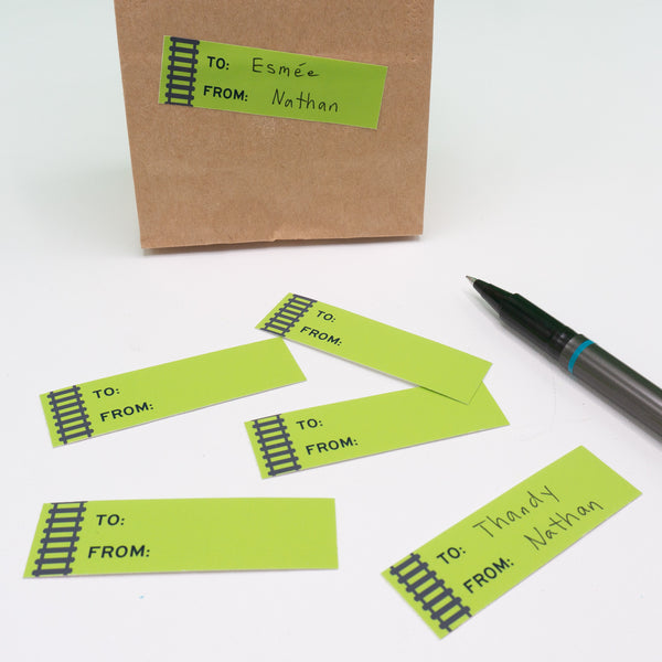 Rectangular to and from gift tag sticker labels with black railroad tracks running along the left side. Pictured here on a goodie bag.