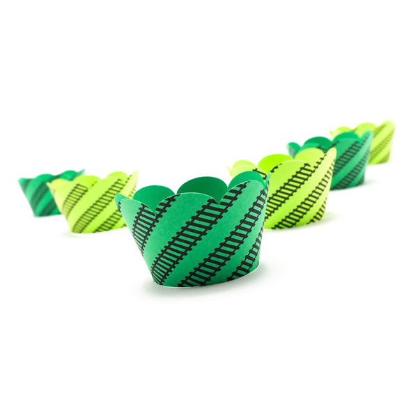 Bright green cupcake wrappers in two shades. Black railroad tracks wrap around at an angle. And the top edge of the wrapper is scalloped.