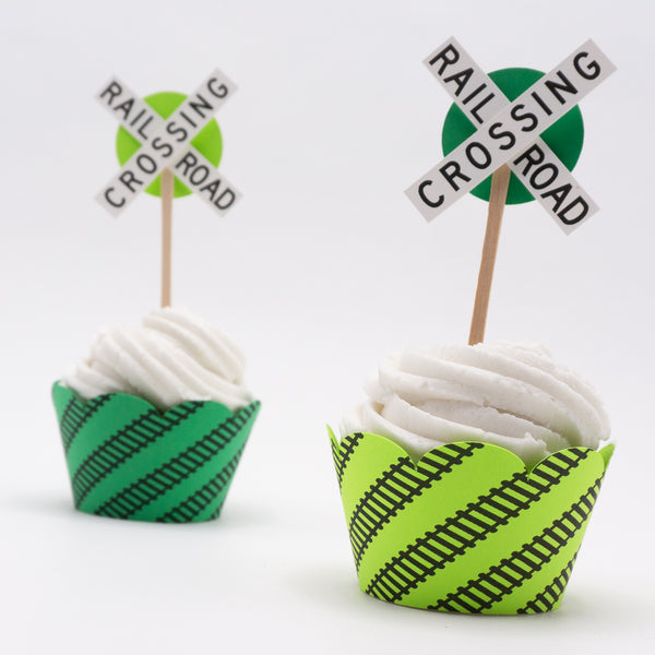 Bright green cupcake wrappers in two shades. Black railroad tracks wrap around at an angle. And the top edge of the wrapper is scalloped. Pictured here with cupcakes inside.