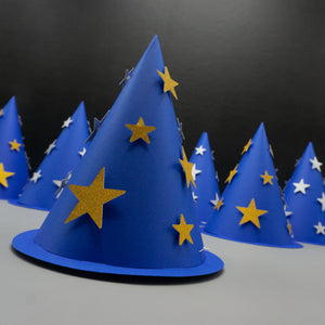 foreground hat is dark blue with shimmering gold stars, while the five hats in the background are slightly out of focus—two with gold stars and three with silver. These cone hats combine the look of traditional party hats with magical wizard costume accessories.