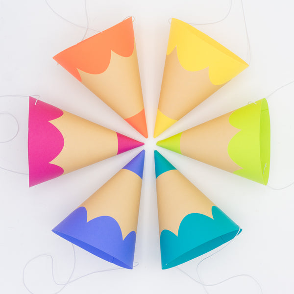 traditional cone-shaped party hats that look just like colored pencils. They are arranged their sides and in a circle, to resemble a color wheel.