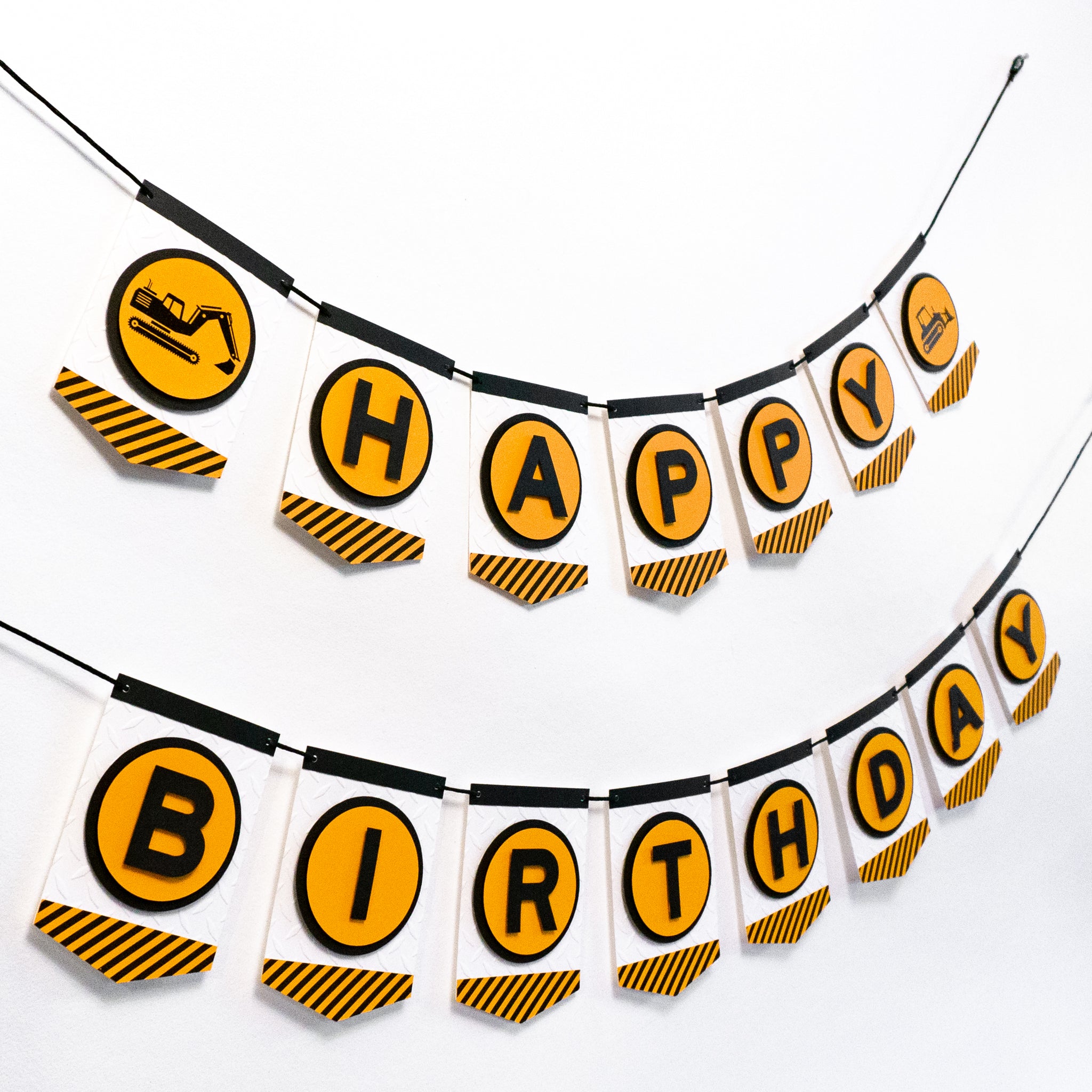 A construction zone themed happy birthday banner. Each letter is in an orange circle and on a separate pennant. Strung on a black cord.