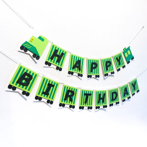 A birthday banner hanging on a wall, fashioned to look like a green freight train. Each pennant is a cargo car with one letter on it.